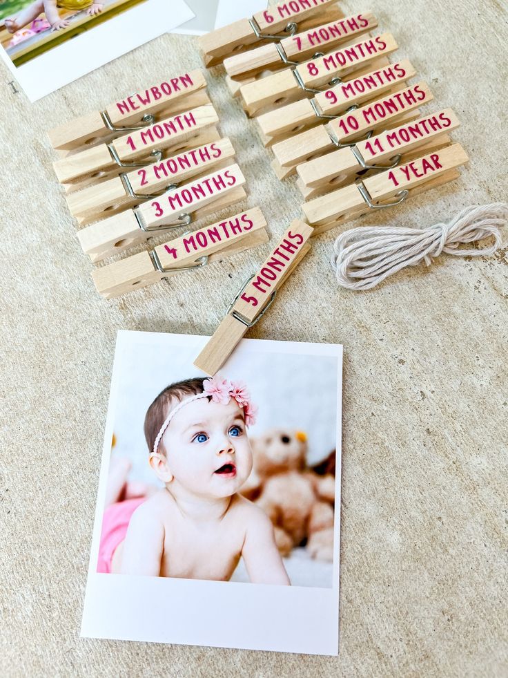 a baby's first year photo is displayed with clothes pins and magnets on the floor