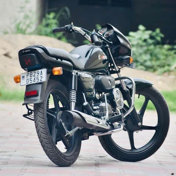 a black motorcycle parked on top of a brick road