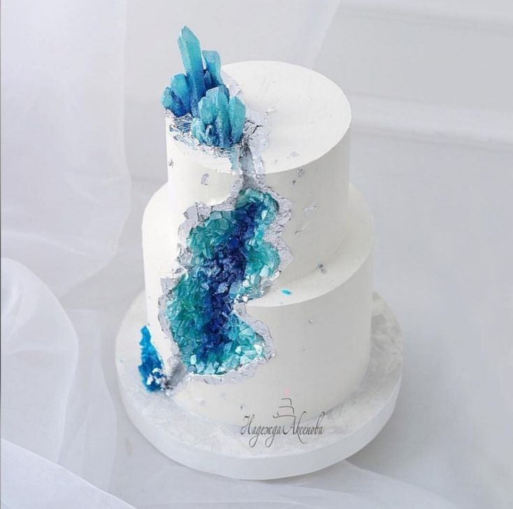 a three tiered white cake with blue icing and frosting on it's side