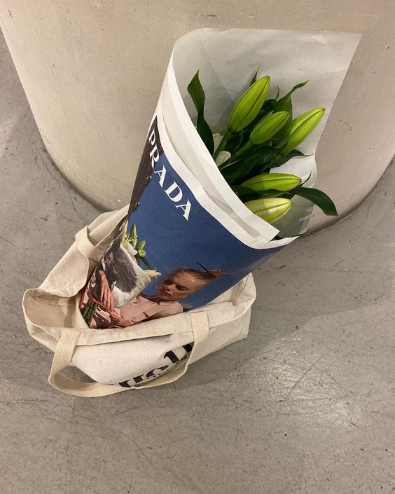 a bouquet of flowers is wrapped in a tote bag and sitting on the ground