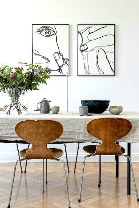 a dining room table with chairs and artwork on the wall in the backround