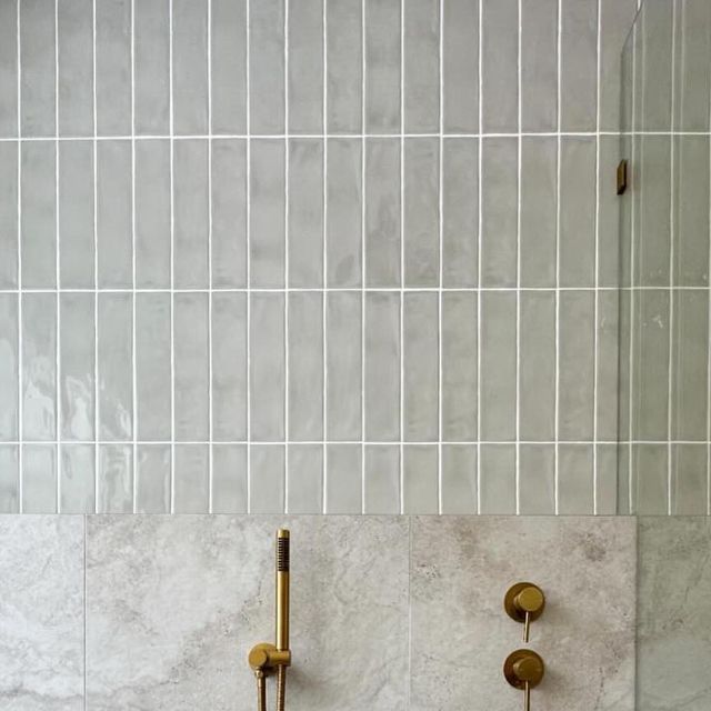 two gold faucets are mounted to the wall in a bathroom with white tile