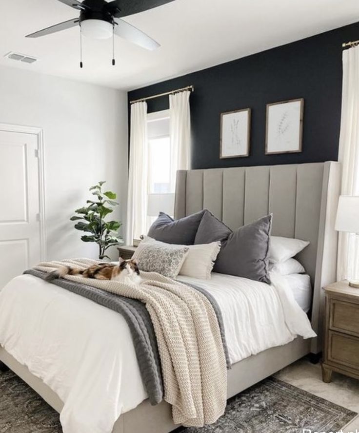 a bedroom with black walls, white bedding and gray accents is pictured in this image