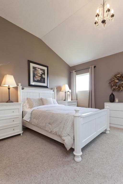 a white bed sitting in a bedroom next to two lamps on either side of the bed