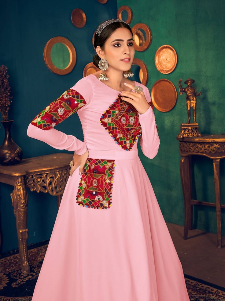 Look pretty adorning this pink color Anarkali gown in georgette material embellished with gamthi embroidery, mirror, and pearl work.
The gown comes with crepe inner material. 
The pink gown is semi-stitched can be customized up to 42 inches and the gown length is 58 inches. 
Pink color gown with gamthi work look amazing traditional can be worn at festivals like Navratri.
Disclaimer: This gown will not come with a can-can, bottom, and dupatta. Pink Kurta With Embroidered Border For Diwali, Pink Embroidered Kurta For Diwali, Pink Wedding Kurta With Embroidered Border, Bollywood Style Pink Kurta With Embroidered Border, Pink Anarkali Set With Embroidered Border, Fitted Pink Kurta With Embroidered Border, Pink Bollywood Gown For Traditional Ceremonies, Pink Kurta With Mirror Work For Festivals, Festive Pink Anarkali Set With Embroidered Border