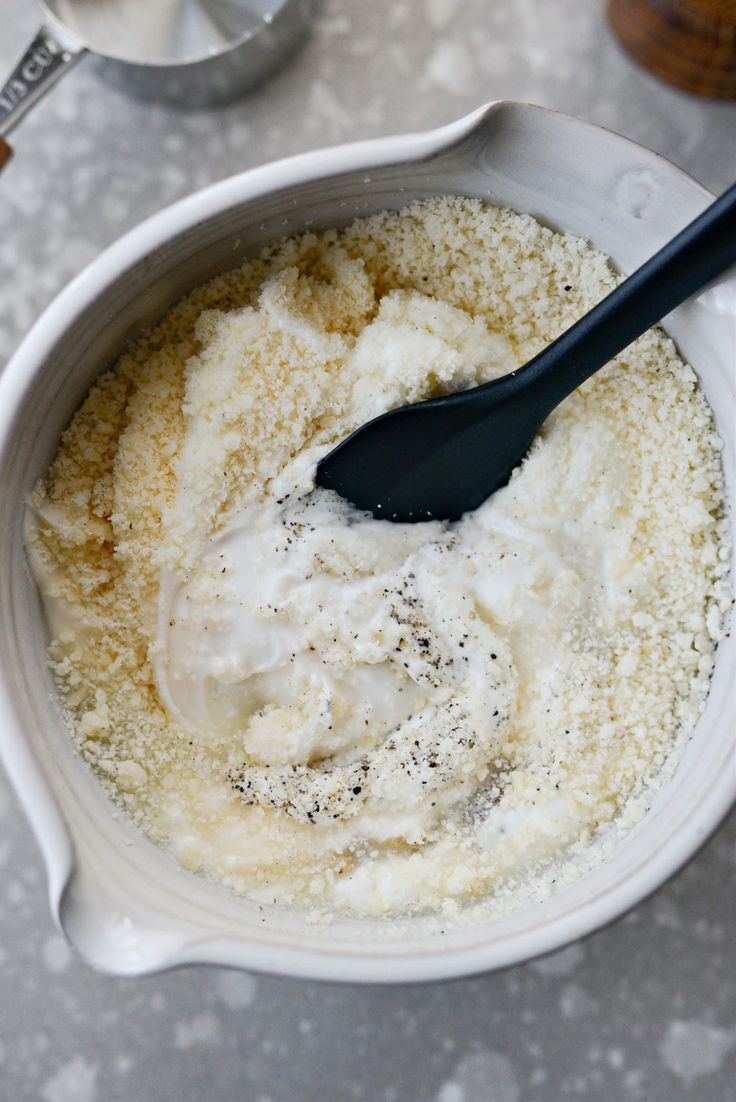 a white bowl filled with some kind of food and a black spoon on top of it