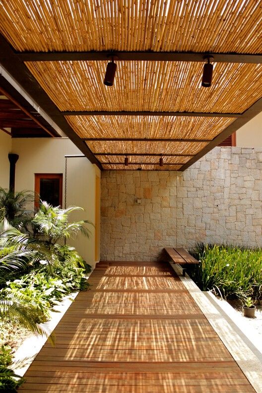 an outdoor covered walkway with benches and plants