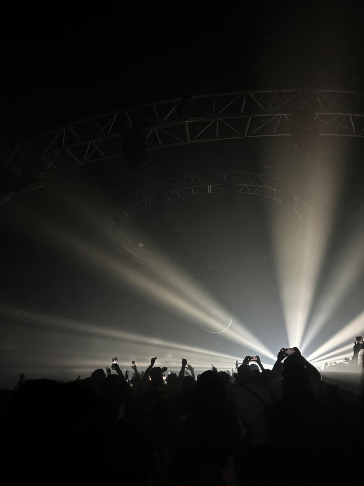 a large group of people standing in front of a stage with bright lights on it