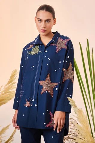 Navy blue oversized shirt with contrast thread and bead embroidered star motifs and patch pockets in front.
Component: 1
Pattern: Embroidered
Type Of Work: Thread and Beads
Neckline: Spread Collar
Sleeve Type: Full
Fabric: Poplin
Color: Blue
Other Details: 
High low hem shirt
Patch pockets in front
Closure: Concealed button front
Note: Pant worn by the model is not for sale
Occasion: Party - Aza Fashions Clothing Store Interior, Shirt For Women, Online Tops, Shirt And Pants, Pant Set, Straight Pants, Shirt Pattern, Oversized Shirt, Western Wear