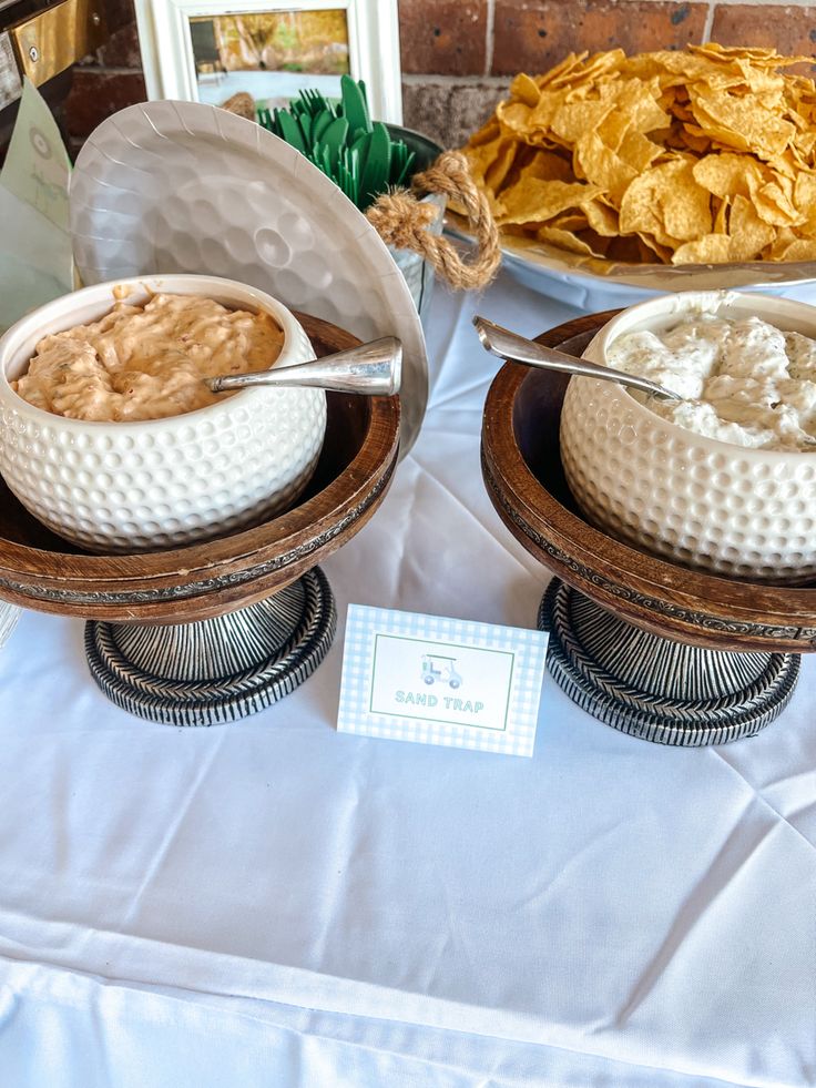 two bowls filled with food sitting on top of a white table cloth covered tablecloth