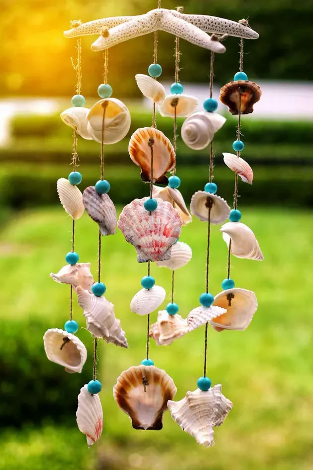 a wind chime with seashells hanging from it's strings in the grass