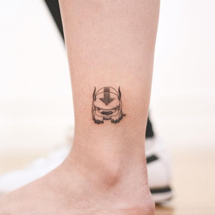 a small tattoo on the ankle of a woman's foot with an image of a bull