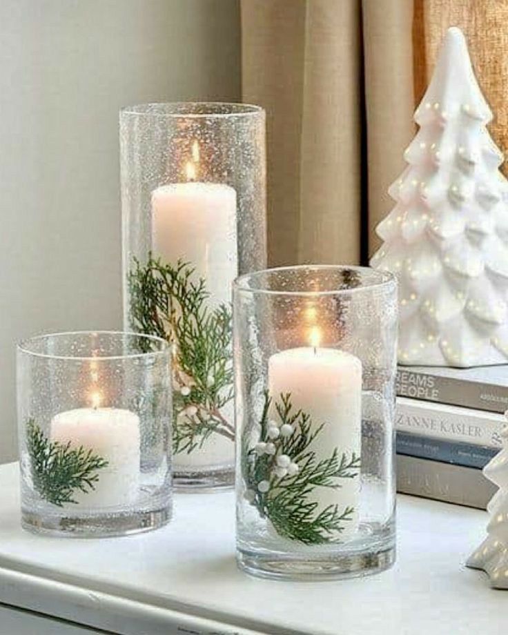 three candles sitting on top of a white table next to a book and christmas tree