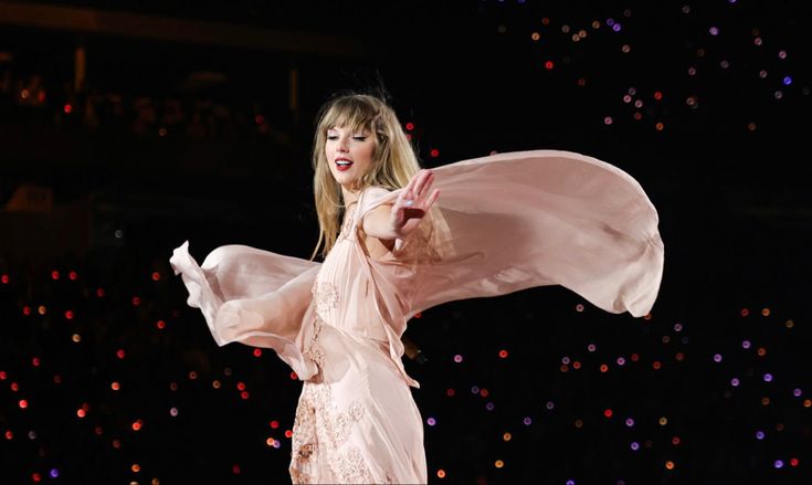 a woman in a white dress is on stage with her arms spread out to the side