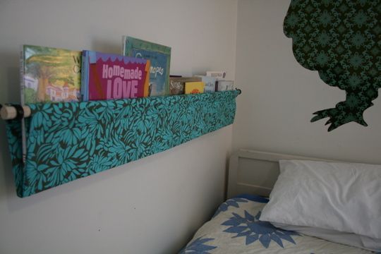 there is a bed with books on the headboard and an animal wall hanging above it