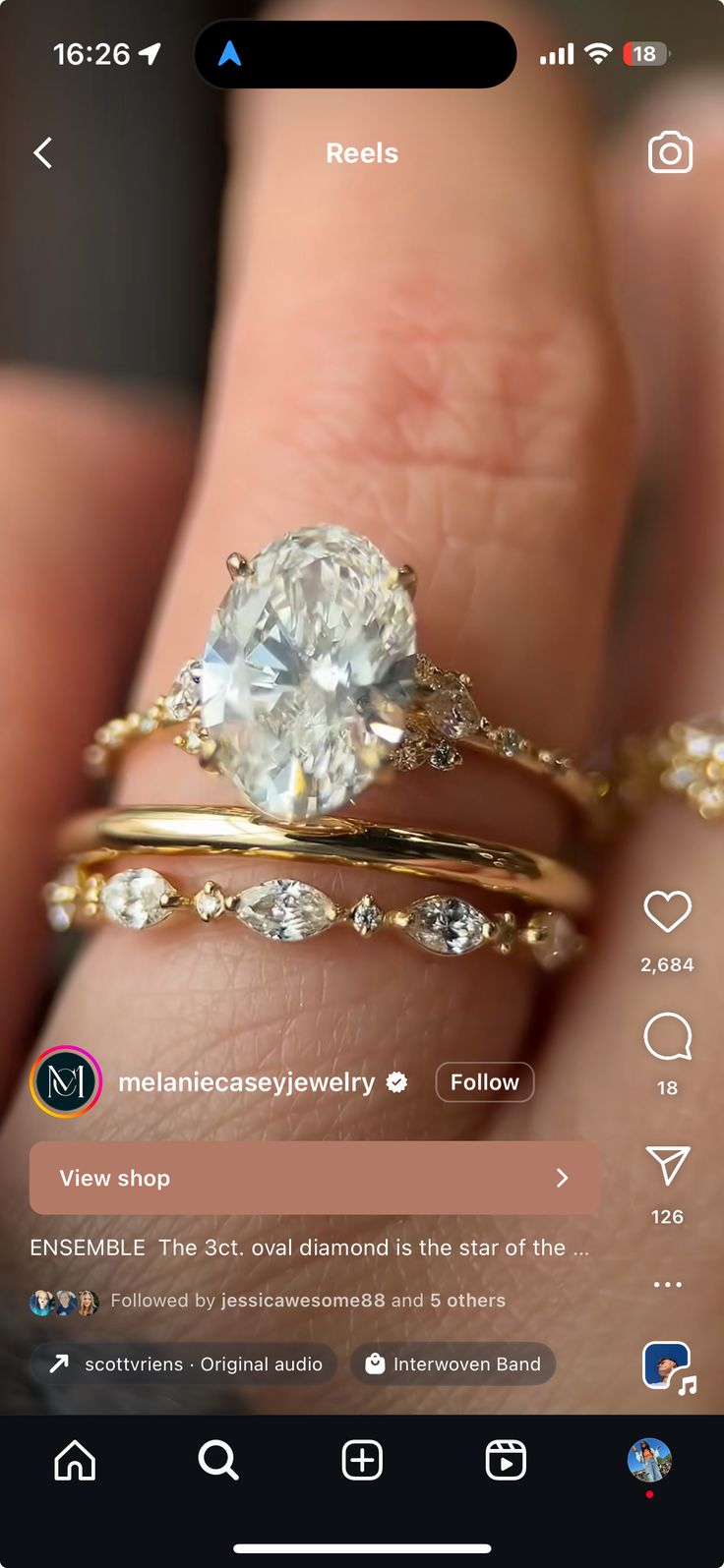 a person's hand holding two gold rings and an engagement ring on their finger