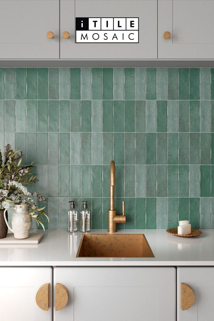 a kitchen with green tiles on the backsplash and gold faucet handles