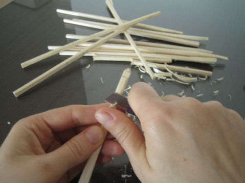 a person is making something out of matchesticks on a table with one hand