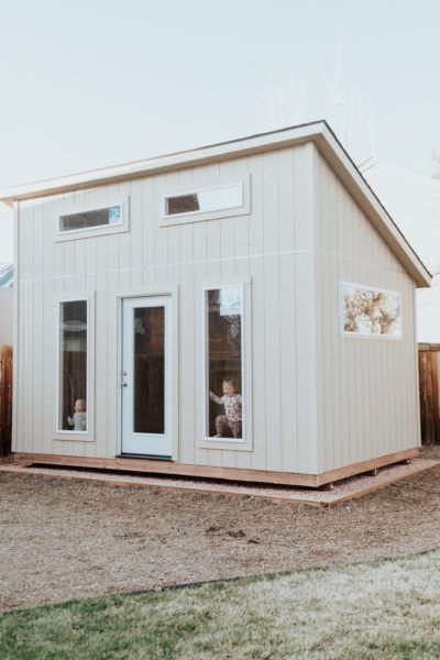 a small white house sitting on top of a grass covered field