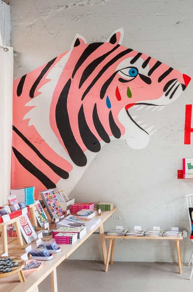 a large pink tiger head hanging on the wall next to a table with books and magazines