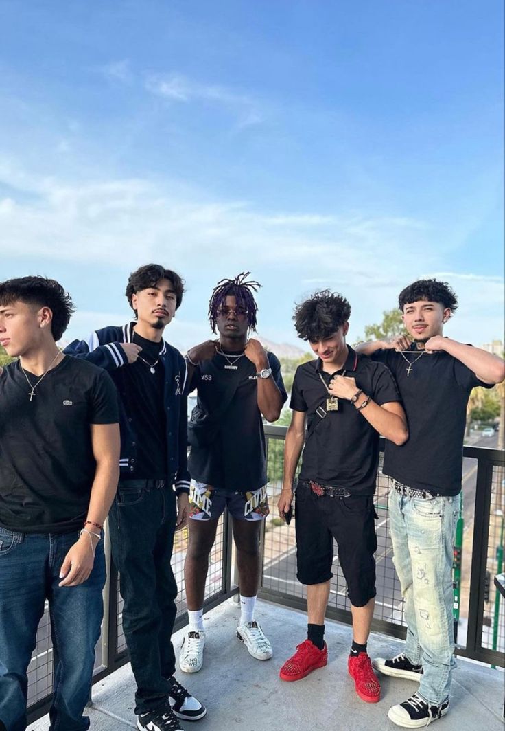 five young men standing on a balcony with their arms around each other and looking at the camera