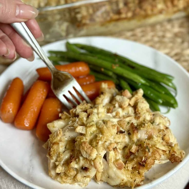 a white plate topped with carrots and chicken next to green beans