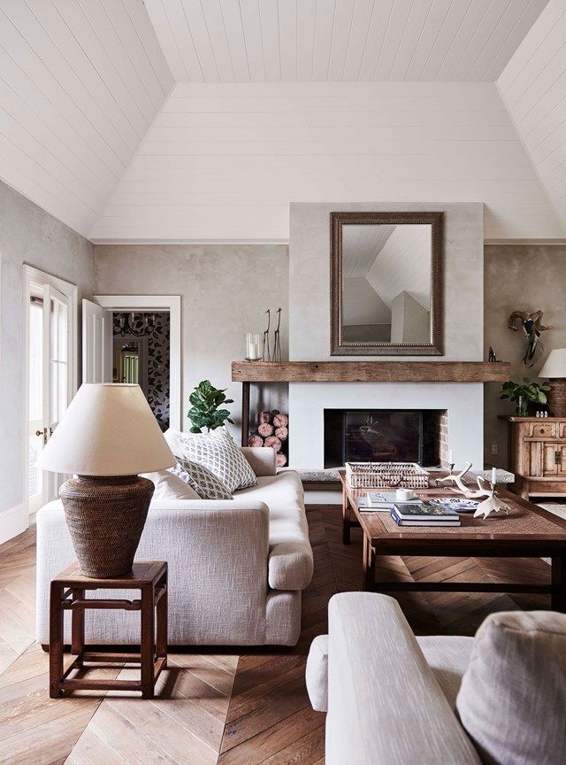 a living room filled with furniture and a fire place under a mirror on the wall