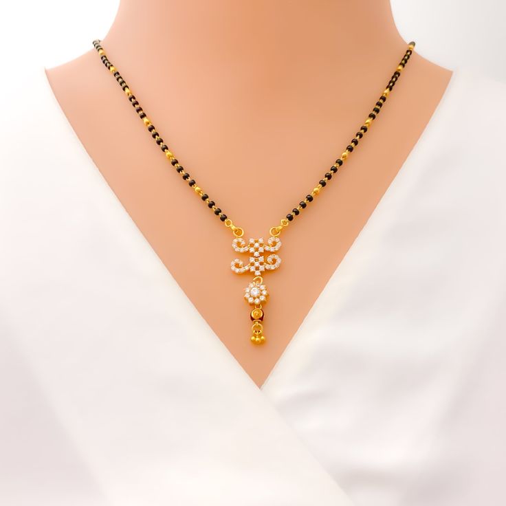 This 22k gold Mangal Sutra, weighing 9.9 grams, radiates festive charm with its stunning combination of black beads and cubic zirconia stones. The necklace measures 18" in length with a 1.5" drop, and adjustable 1" links offer a flexible fit. Finished in yellow gold, its hook lock ensures secure wear while adding to its elegance. Ideal for special occasions, this piece captures the perfect blend of tradition and sparkle, making it a dazzling addition to your jewelry collection. PRODUCT DETAILS Gold Purity(karat): 22k Item Weight(grams): 9.9 Item Finish: Yellow Gold Stone: Black Bead + Cubic Zirconia Necklace Length: 18" Drop Length: 1.5" Adjustable Links: 1" Links Lock Style: Hook Lock Black 22k Gold Jewelry With Round Beads, Black 22k Gold Jewelry As A Gift, Black 22k Gold Jewelry Gift, Festive Black Necklace In 22k Gold, Festive Black Necklace With Gold Beads, Black 22k Gold Jewelry For Wedding, Black 22k Gold Wedding Jewelry, Festive Gold Necklace With Black Beads, Festive Gold Necklaces With Black Beads