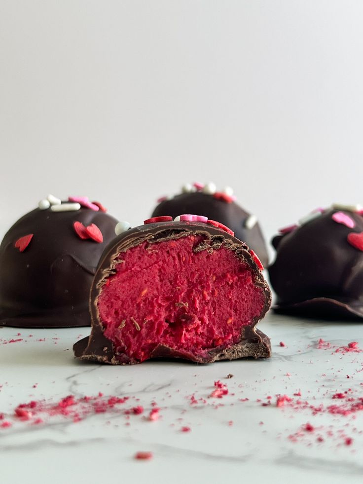 three chocolate truffles with pink and white sprinkles on the side