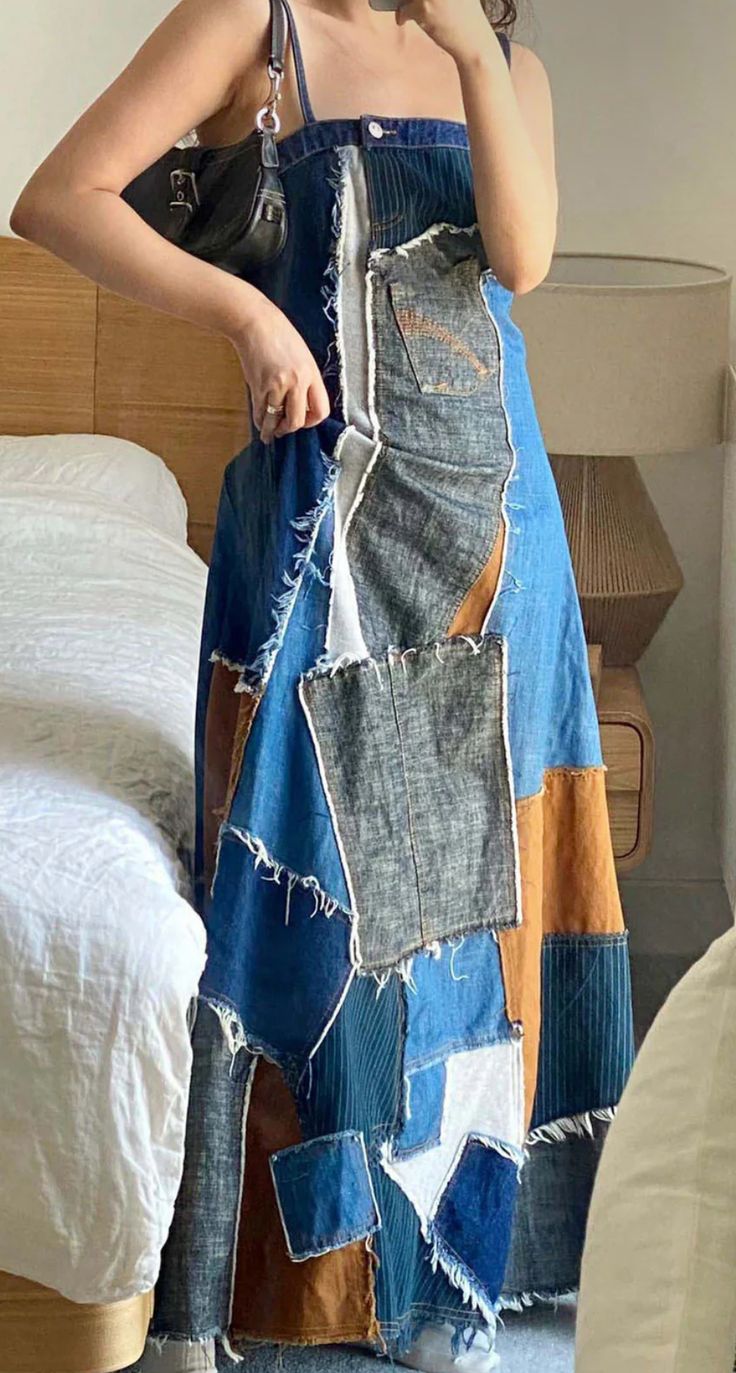 a woman in a blue dress is taking a selfie with her cell phone while standing next to a bed