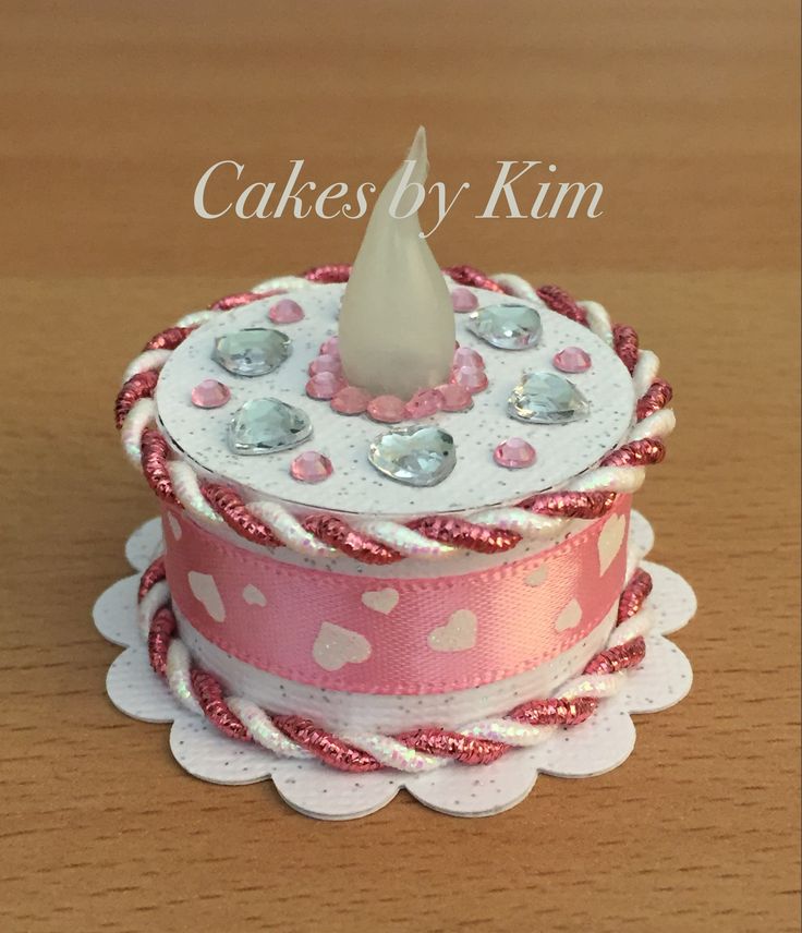 a pink and white cake with a candle on top