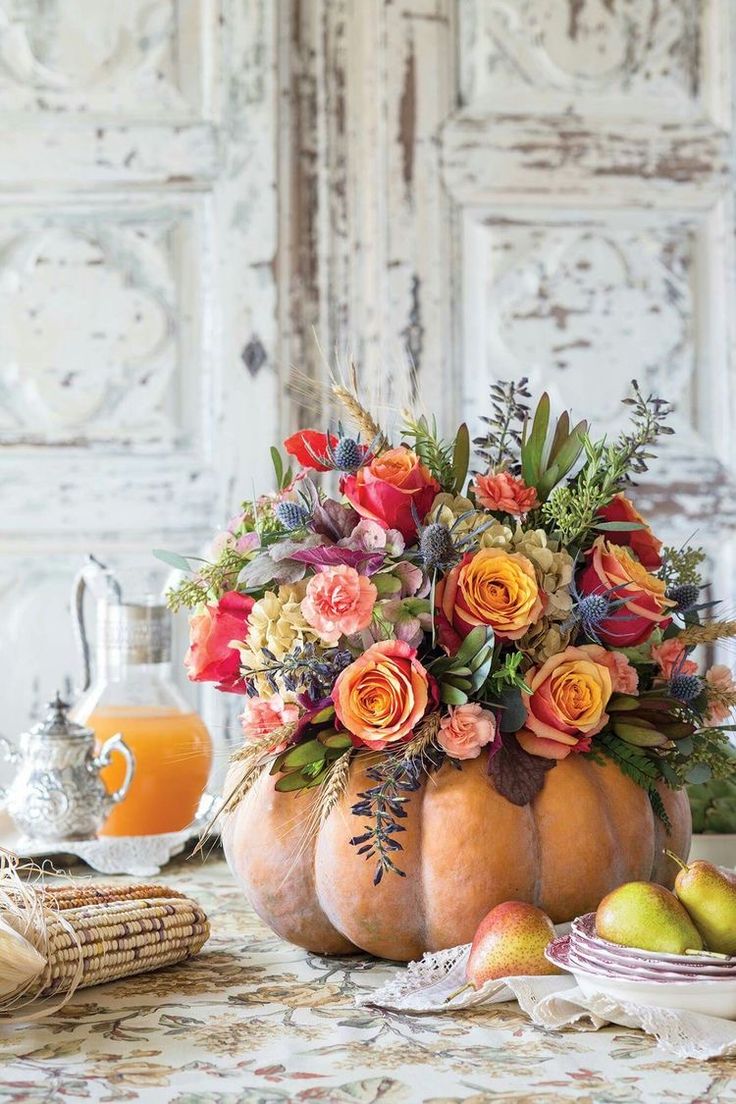 a vase filled with lots of flowers sitting on top of a table next to fruit