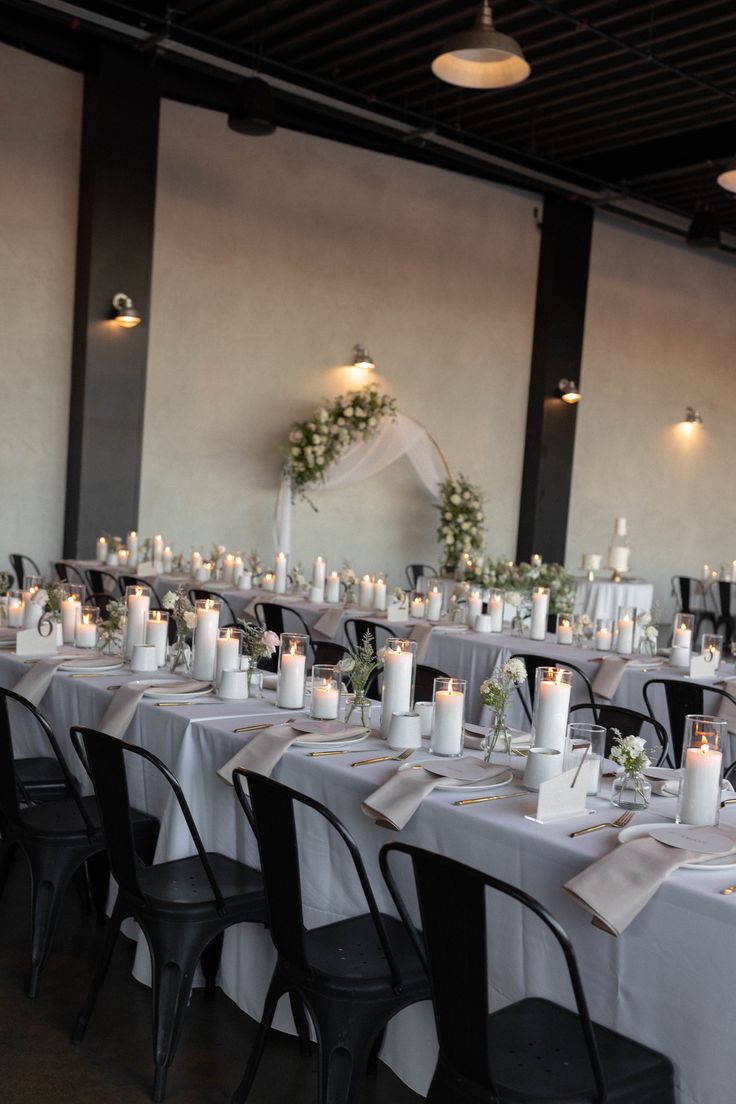 a long table is set with candles and place settings for an elegant wedding reception at the venue