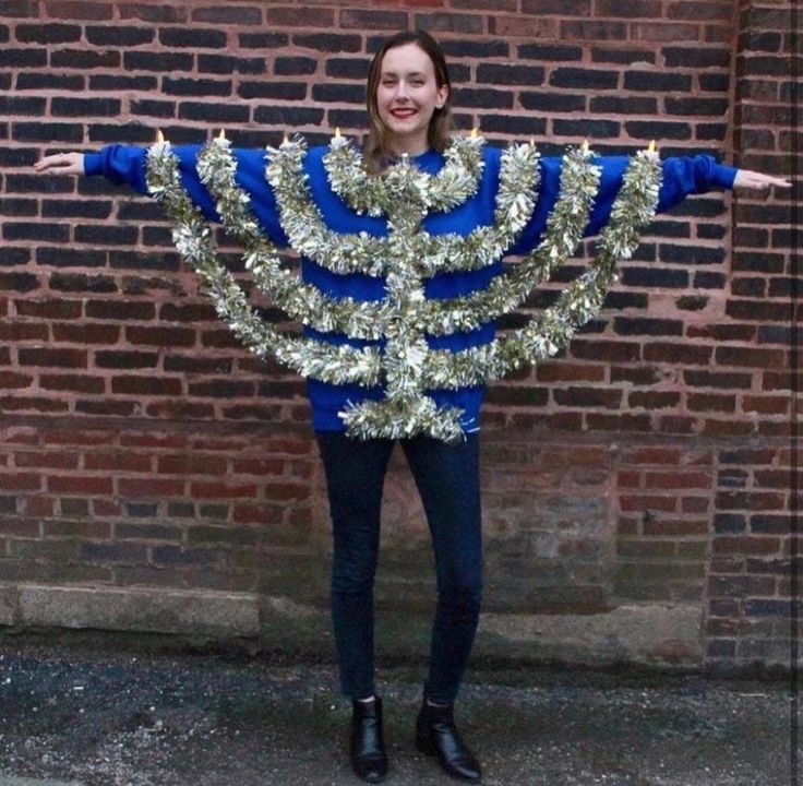 a woman standing in front of a brick wall wearing a blue and white striped sweater