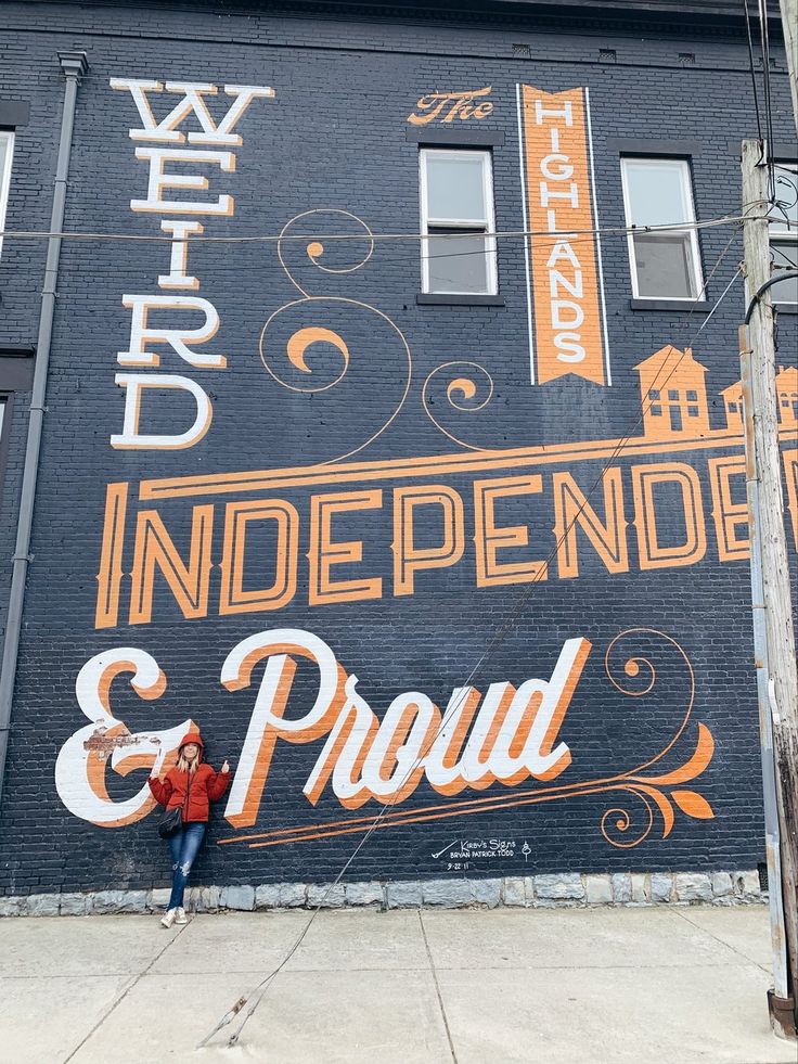 a person standing in front of a large mural on the side of a building