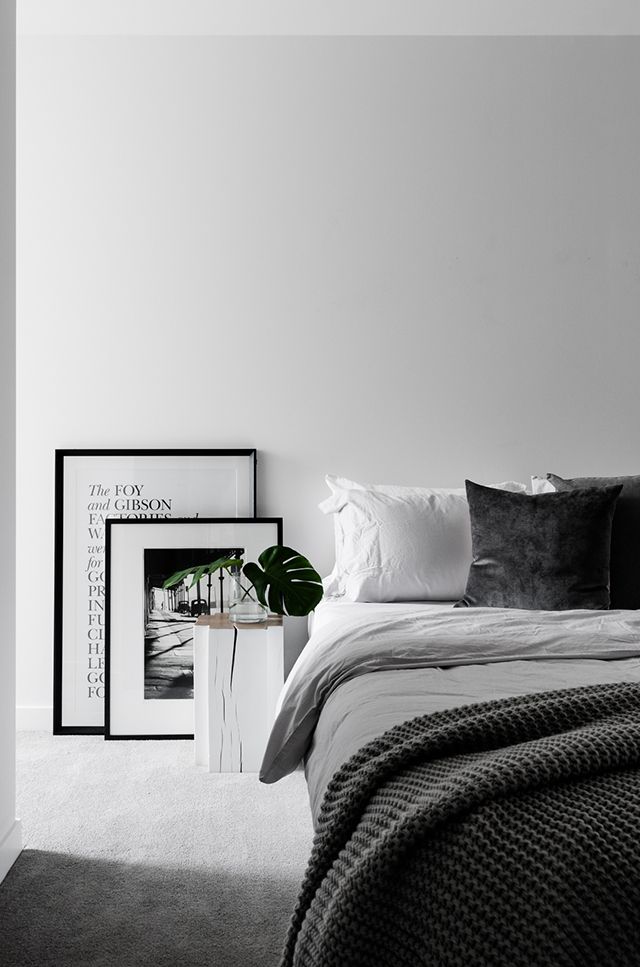 a bedroom with white walls and grey carpeting, black and white decor on the wall