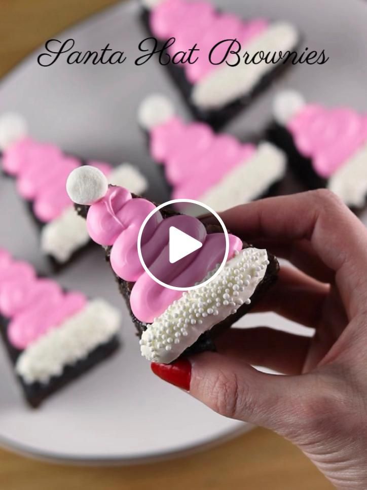 a person is holding up some pink and white decorated cupcakes on a plate