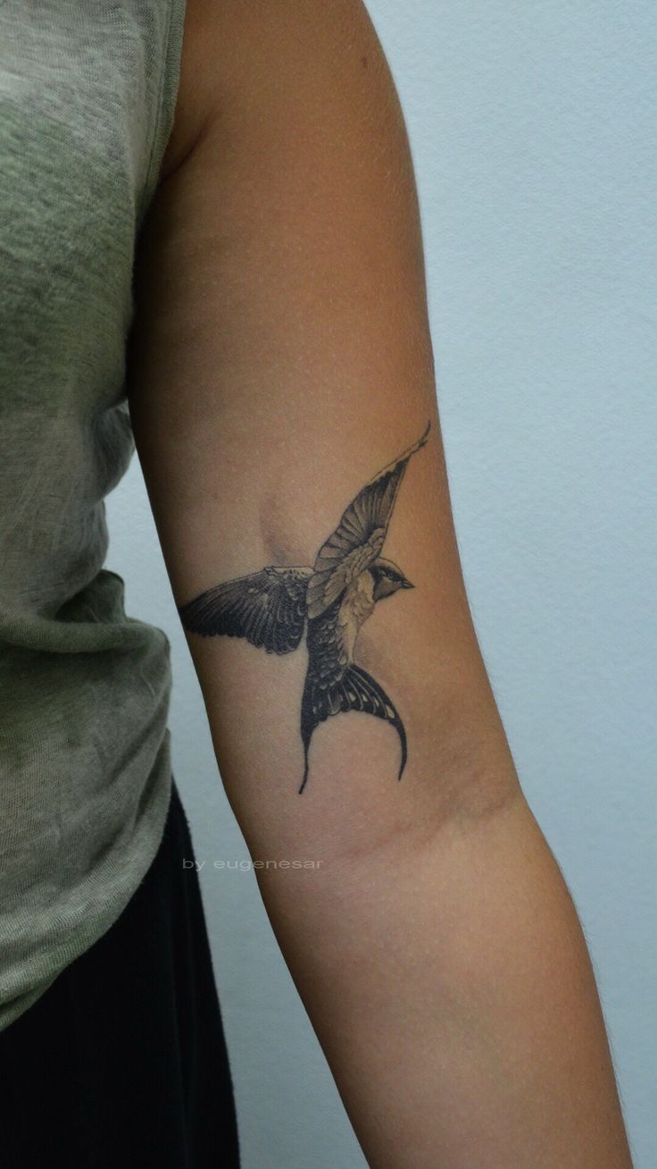 a woman's arm with a bird tattoo on the left side of her arm