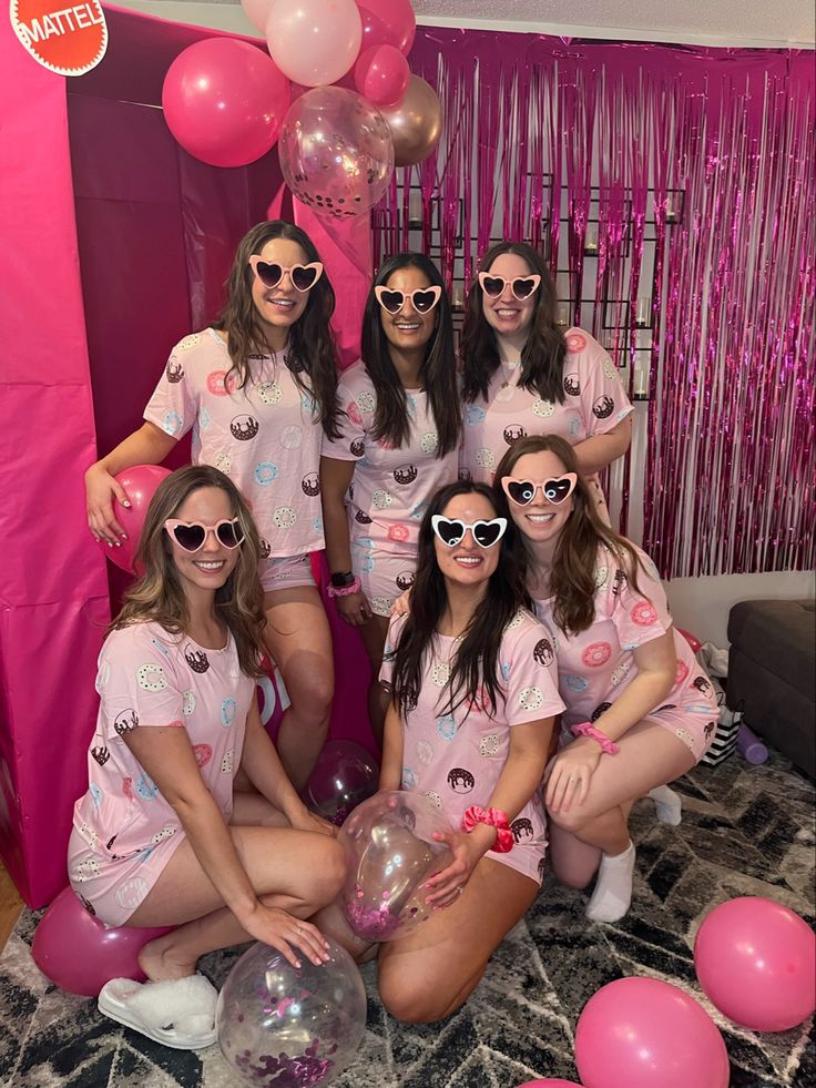 a group of women in pink shirts and white shorts posing for a photo with balloons