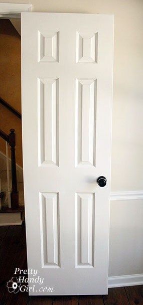 an open white door in the corner of a room with wood flooring and stairs