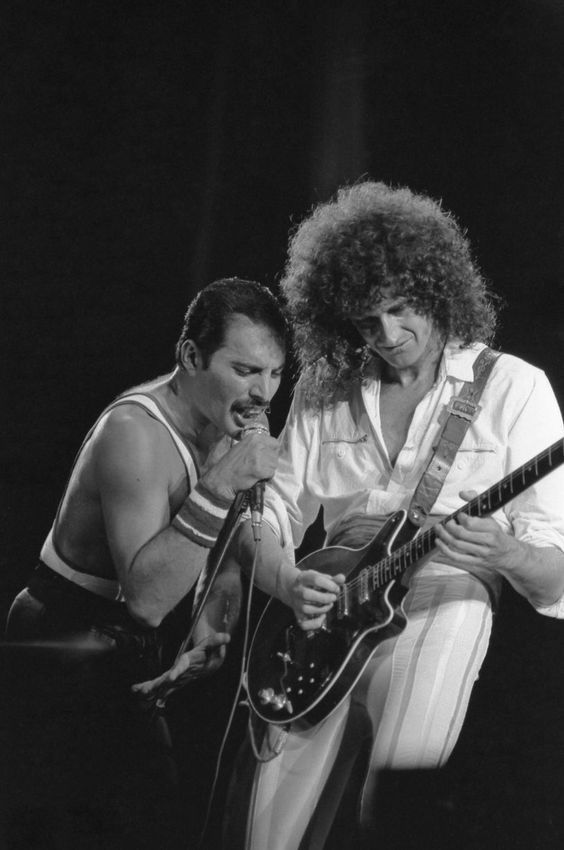 two men playing guitars and singing into microphones