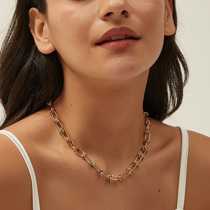 DESCRIPTION & DETAILS This geometric shaped linked knot chain necklace is a statement piece which is following the latest trend, that is perfect to wear everyday or on any special occasion. This perfect balance of minimal and statement necklace making it also great for wear on it's own but also layers perfectly with any of our delicate or statement necklaces. Plating: 14k Gold Materials: 14K Gold on Stainless Steel Measurements: 47 cm Hypoallergenic SUSTAINABILITYIn-house plating - All pieces ar Chic Metal Necklace With Paperclip Chain, Chic Metal Paperclip Chain Necklace, Elegant Toggle Necklace With Chunky Chain, Chic Metal Necklaces With Rectangular Links, Modern Link Toggle Necklace, Minimalist Toggle Necklace With Delicate Chain, Modern Chunky Chain Toggle Necklace, Metal Toggle Necklace With Paperclip Chain, Chic Clavicle Chain Link Necklace