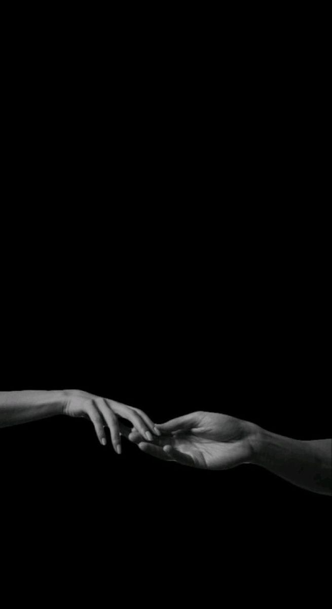 two hands reaching out towards each other in black and white, against a dark background