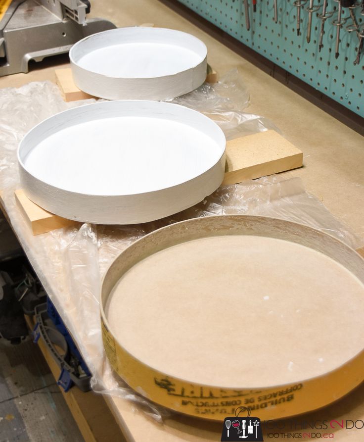 three white plates sitting on top of a table next to some wood planks and plywood