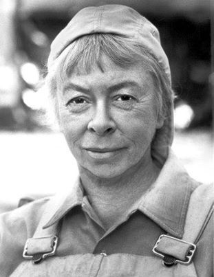 black and white photograph of an older woman wearing overalls with a hat on her head