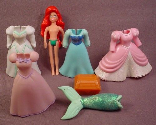 there are many dolls and toys on the table together in this photo, including one little mermaid