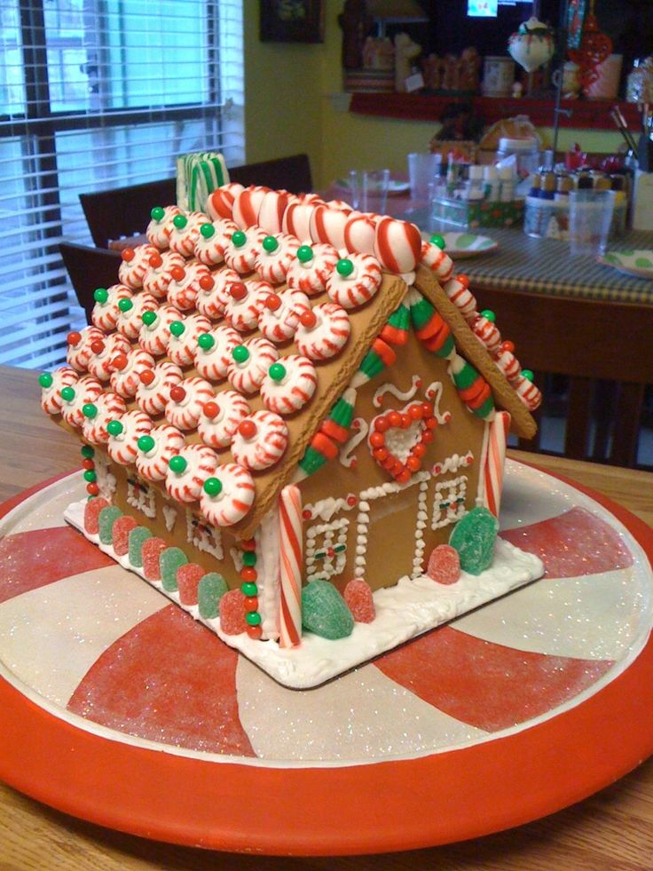 a gingerbread house on a plate with candy canes