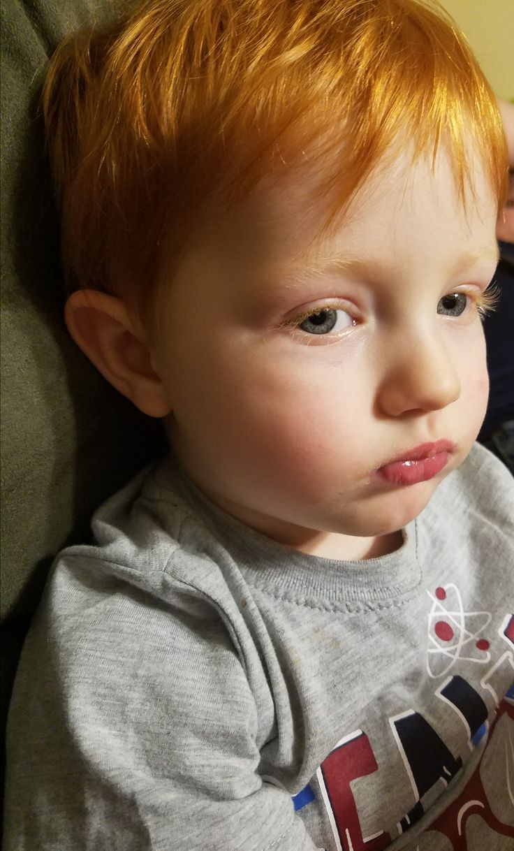 a young boy with red hair sitting in a chair