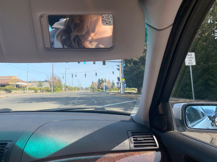 a woman is seen in the rear view mirror of a car as she drives down an empty street