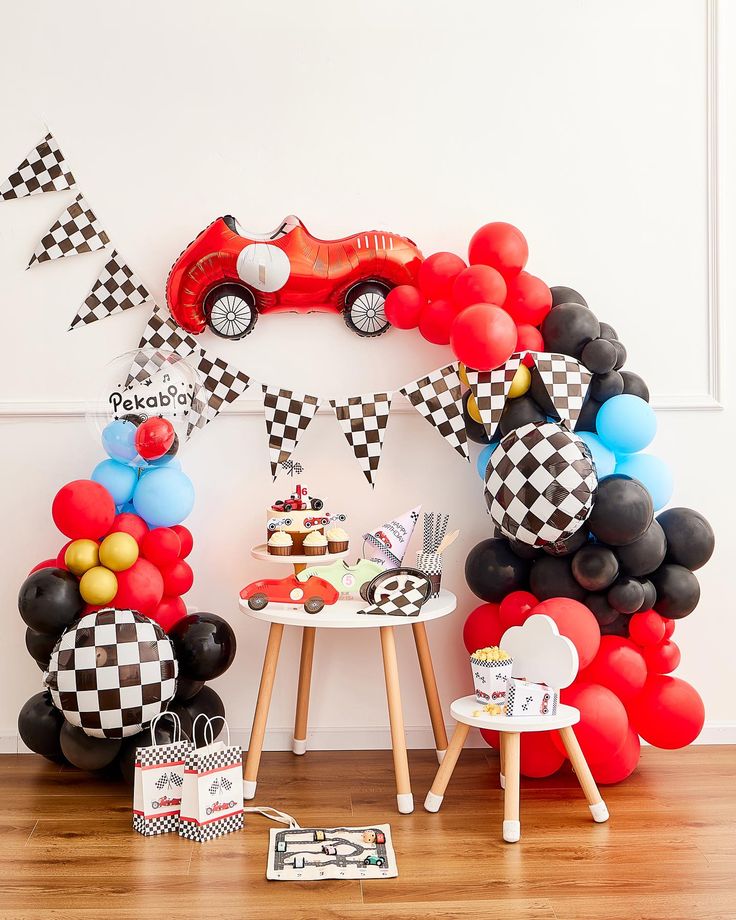 a birthday party with cars and balloons on the wall, including a race car balloon arch